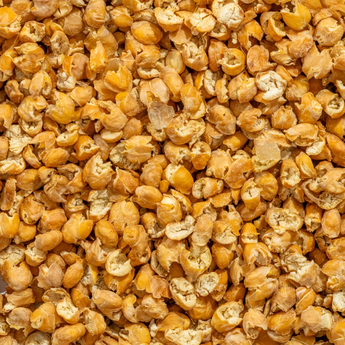 Nahaufnahme von Knusperflakes Kichererbsen. Die Flakes sind hellbraun und liegen dicht an dicht.