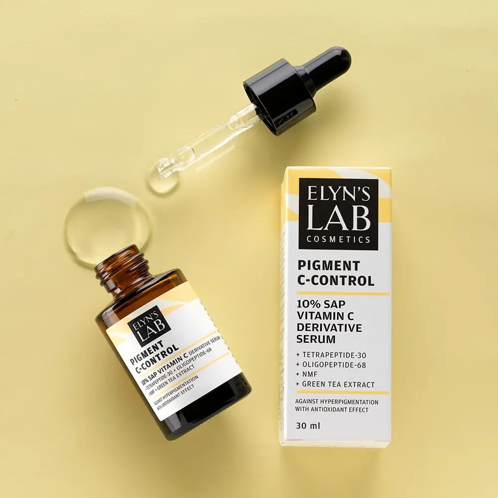 Serumflasche und Verpackung. Pipette daneben. Produktname und Inhaltsstoffe auf dem Etikett. ELYN'S LAB Pigment C-Control Serum.