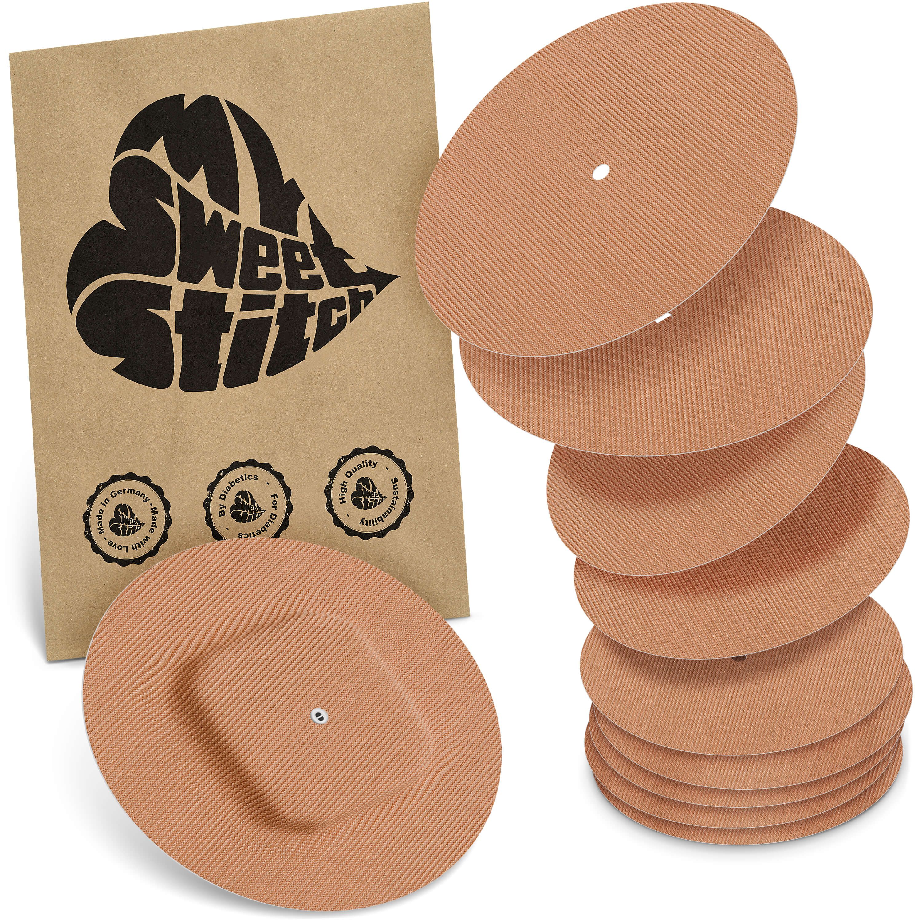 Mehrere runde Pflaster mit einem Loch in der Mitte und eine braune Verpackung mit Logo.