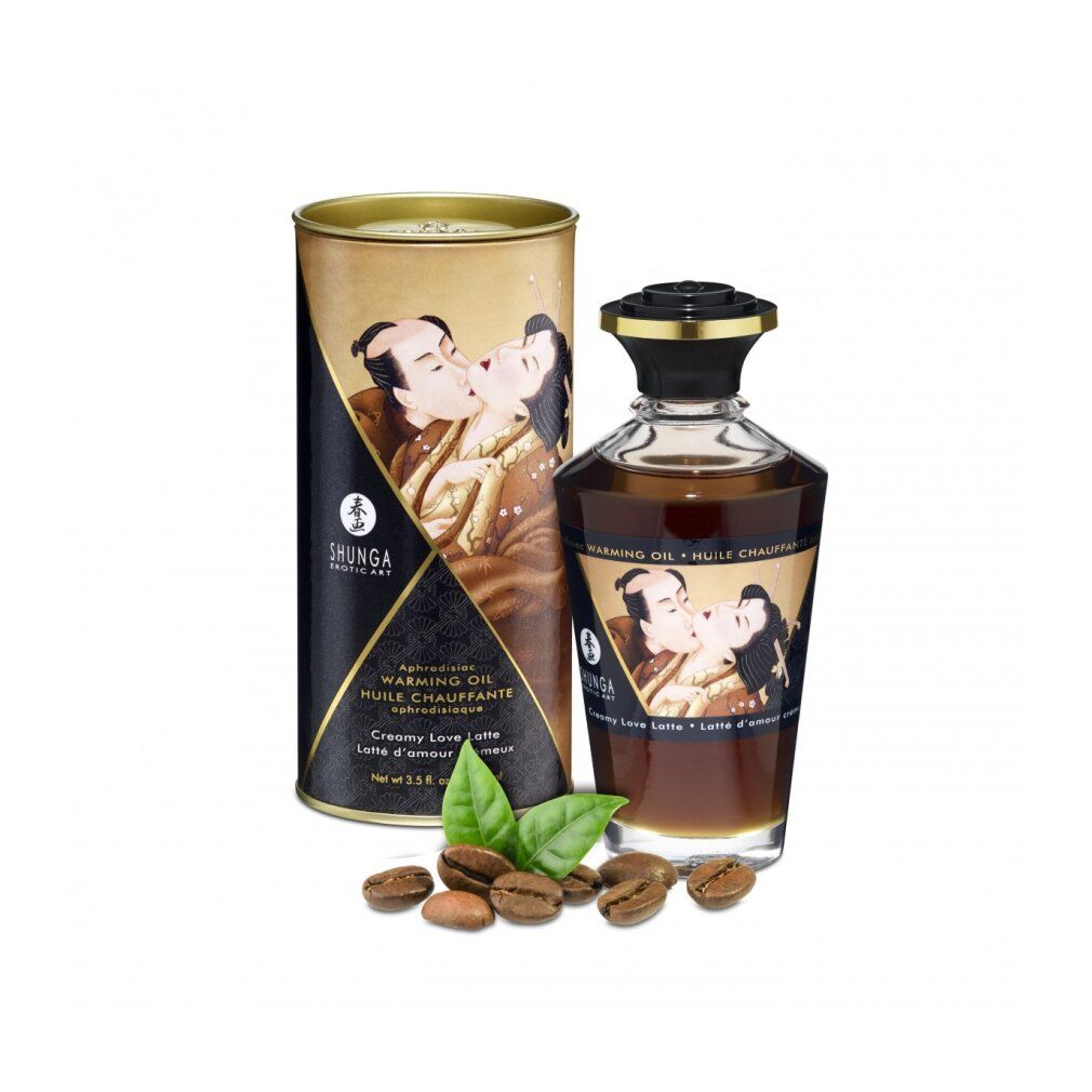 Glasflasche und Dose mit Produktabbildung. Aufschrift: Shunga, Warming Oil, Creamy Love Latte. Kaffeebohnen und Blätter liegen daneben.
