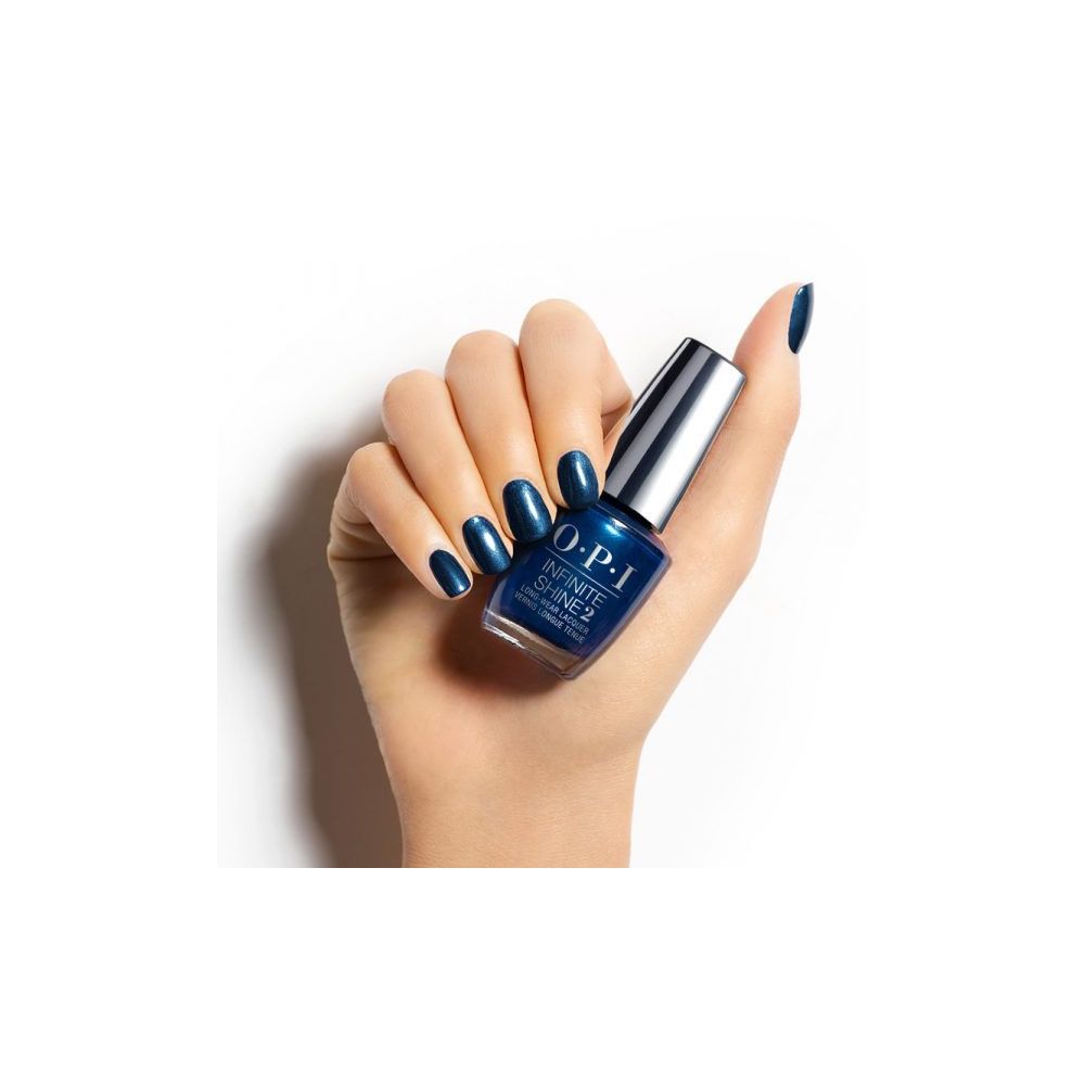 Hand mit lackierten Nägeln und Nagellackflasche. Flasche mit silbernem Deckel, dunkelblauer Lack. OPI Infinite Shine 2.