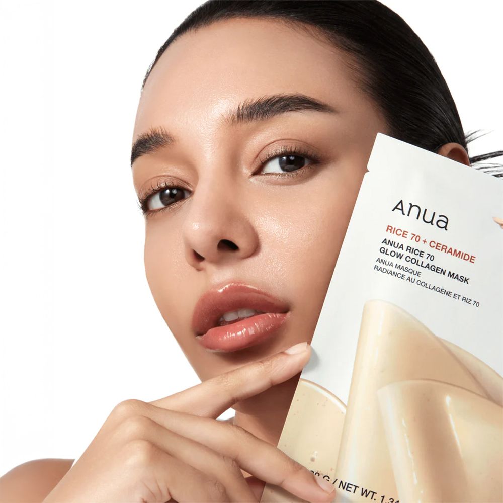Frau hält eine Anua Rice 70 Glow Collagen Maske vor ihr Gesicht.