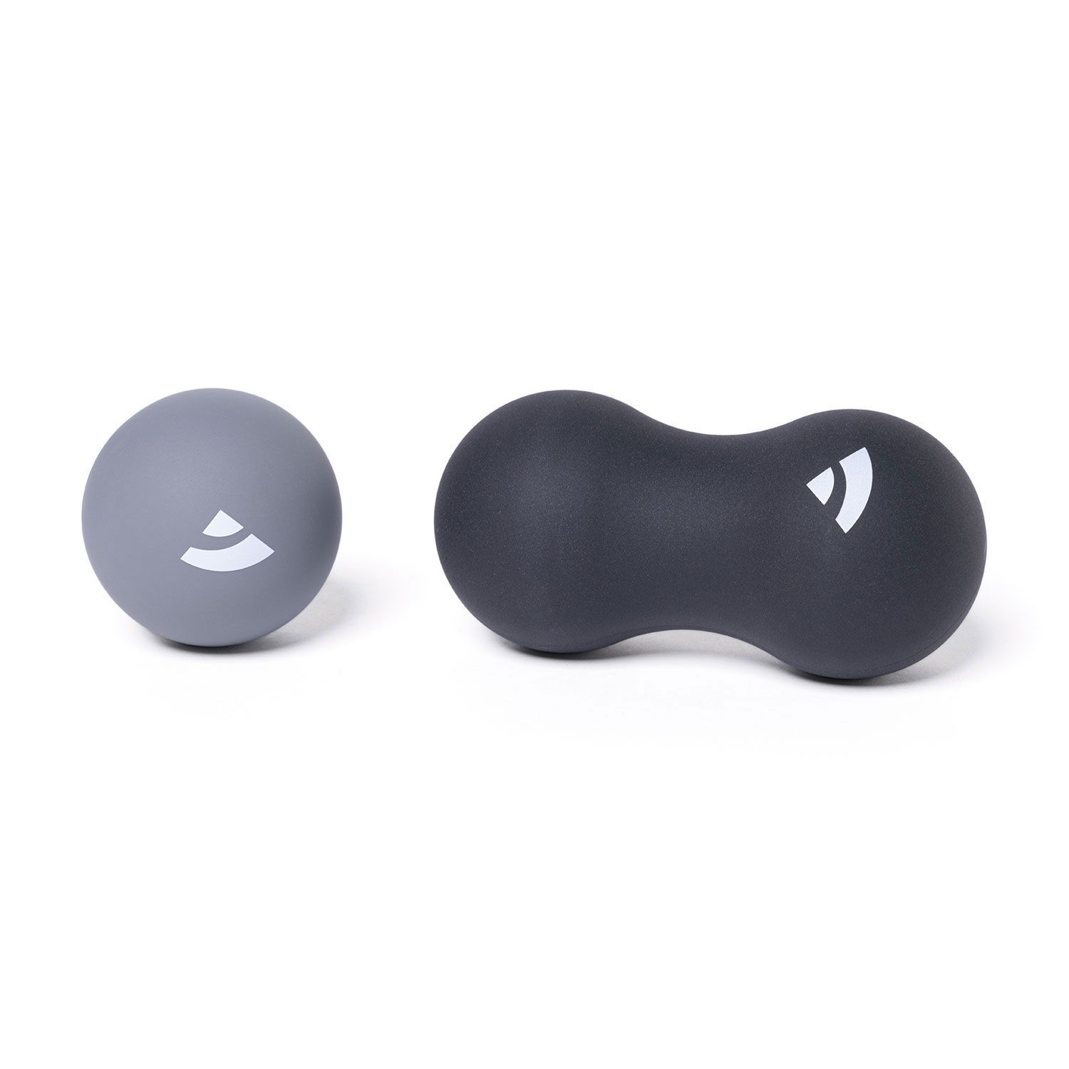 Grauer Massageball und schwarze Erdnuss-Rolle. Beide mit weißem Logo. Auf weißem Hintergrund.