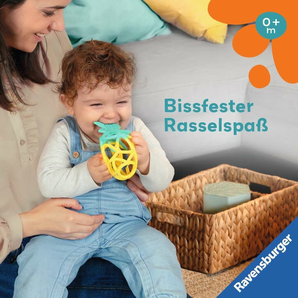 Baby hält Ananas-Greifling im Mund. Gelb-türkise Form. Baby sitzt auf dem Schoß einer Person. Korb im Hintergrund.