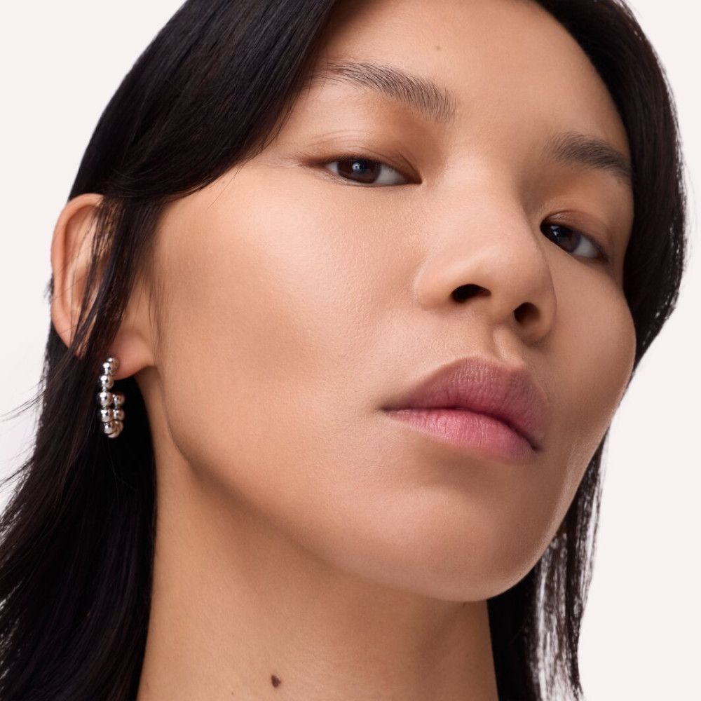 Nahaufnahme einer Frau mit silbernen Ohrringen. Die Ohrringe sind rund und haben eine strukturierte Oberfläche.