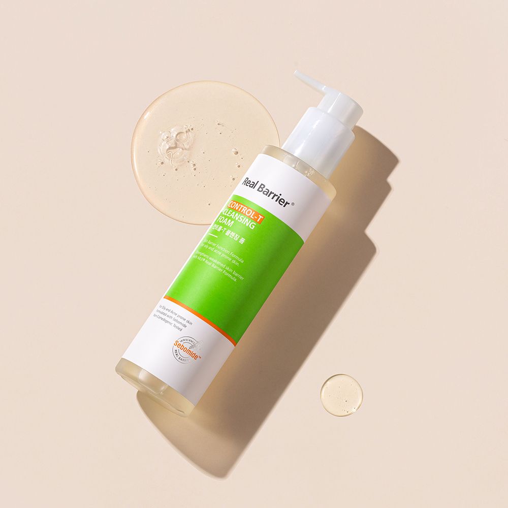 Flasche Real Barrier Control-T Cleansing Foam und zwei Tropfen Flüssigkeit. Auf hellem Hintergrund.