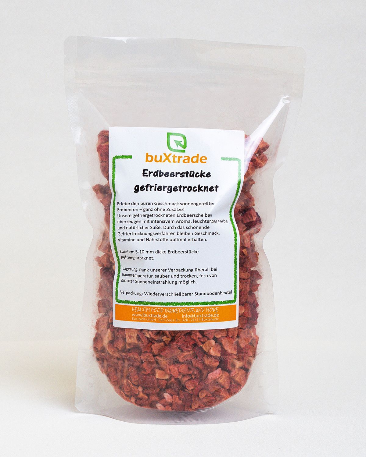 Transparente Verpackung mit gefriergetrockneten Erdbeerstücken. Aufkleber mit Produktinformationen und Logo. Erdbeerstücke sichtbar.