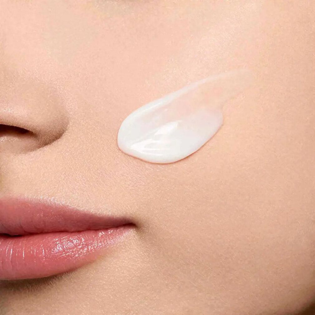 Nahaufnahme von Haut mit aufgetragener Creme. Creme-Strang auf der Haut. Gesichtspartie mit Nase, Lippen und Wangen.