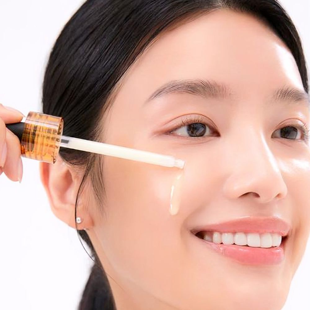 Frau mit Tropfer, der Flüssigkeit auf die Haut aufträgt. Sichtbar: Flasche mit Aufschrift Vitamin Derma Ampoule Brightening, MEDIHEAL.