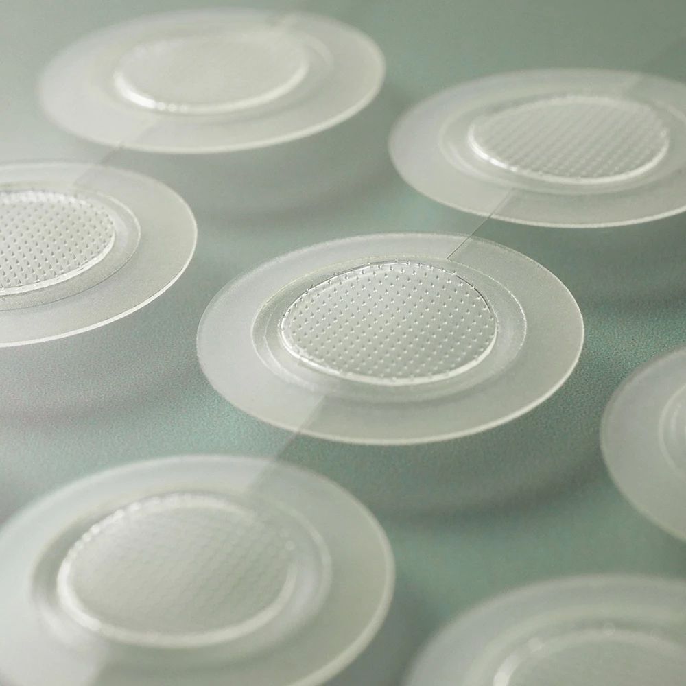 Mehrere transparente, runde Patches mit einem zentralen, strukturierten Bereich. Nahaufnahme.