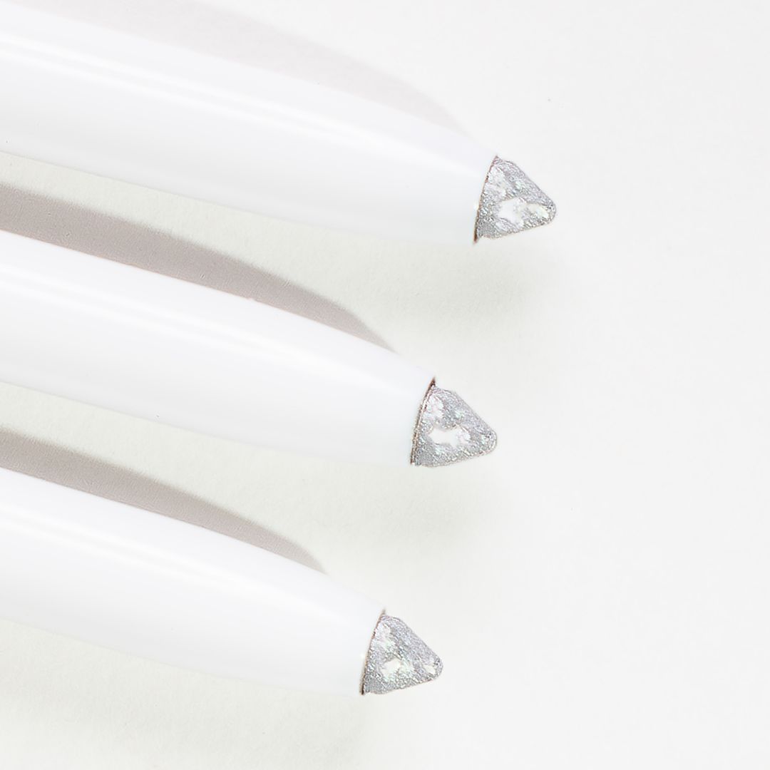 Drei weiße Kajal-Eyeliner-Stifte mit silberner Spitze. Nahaufnahme.