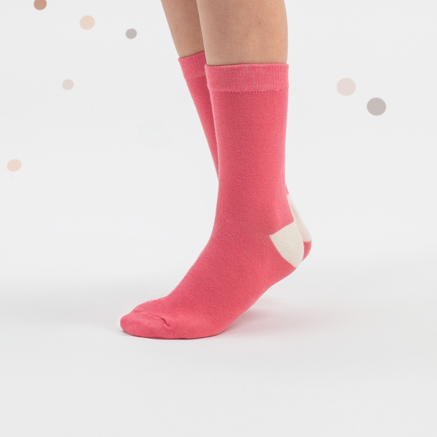 Rosa Socken mit weißem Absatz. Kind trägt die Socken. Hintergrund: weiß mit Punkten.