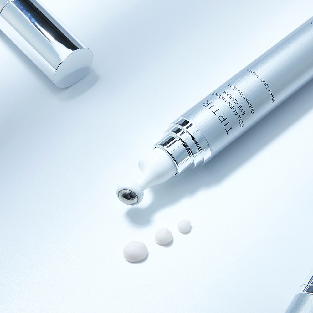 Silberne Tube mit weißem Applikator und Produkt. Drei Tropfen Creme daneben. Text: TIR TIR Collagen Lifting Eye Cream.