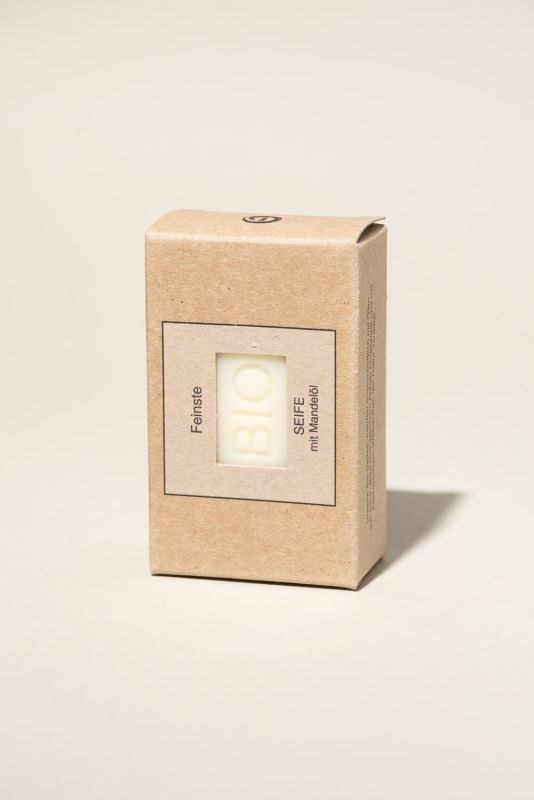 Kartonverpackung mit Seife. Aufschrift "BIO SEIFE mit Mandelöl". Die Seife ist durch ein Fenster sichtbar.