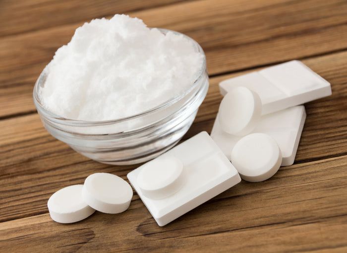 Schüssel mit weißem Pulver und Tabletten auf Holzuntergrund. Runde und rechteckige Formen.