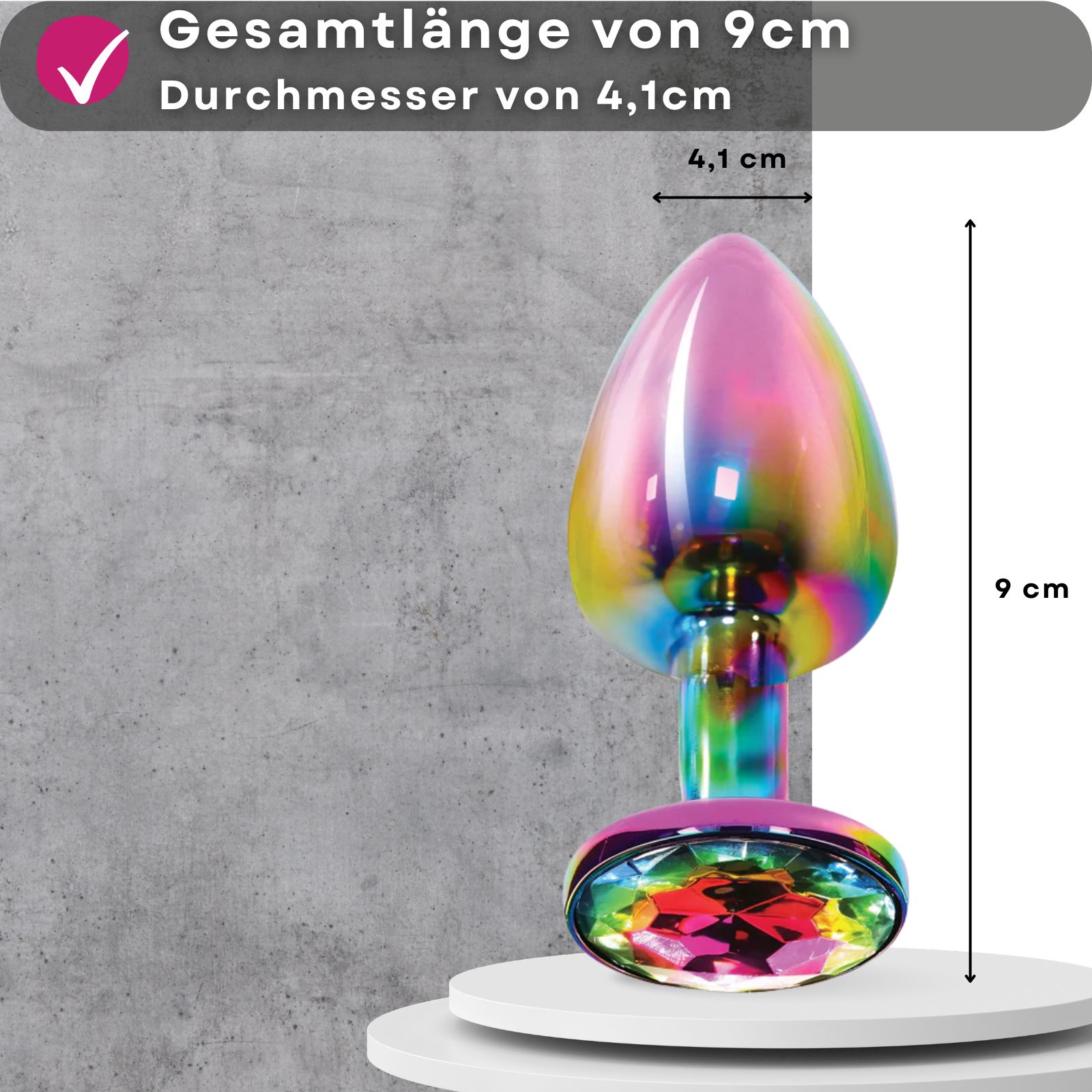 Analplug, mehrfarbig, Metall, mit Zierstein. Maße: 9 cm lang, 4,1 cm Durchmesser. Auf Podest.