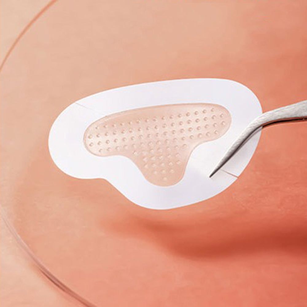 Nahaufnahme eines ACROPASS Reti-Rn Mikrokegel-Pflasters T-Shape. Pflaster mit Mikrokonus-Struktur. Pinzette hält das Pflaster.