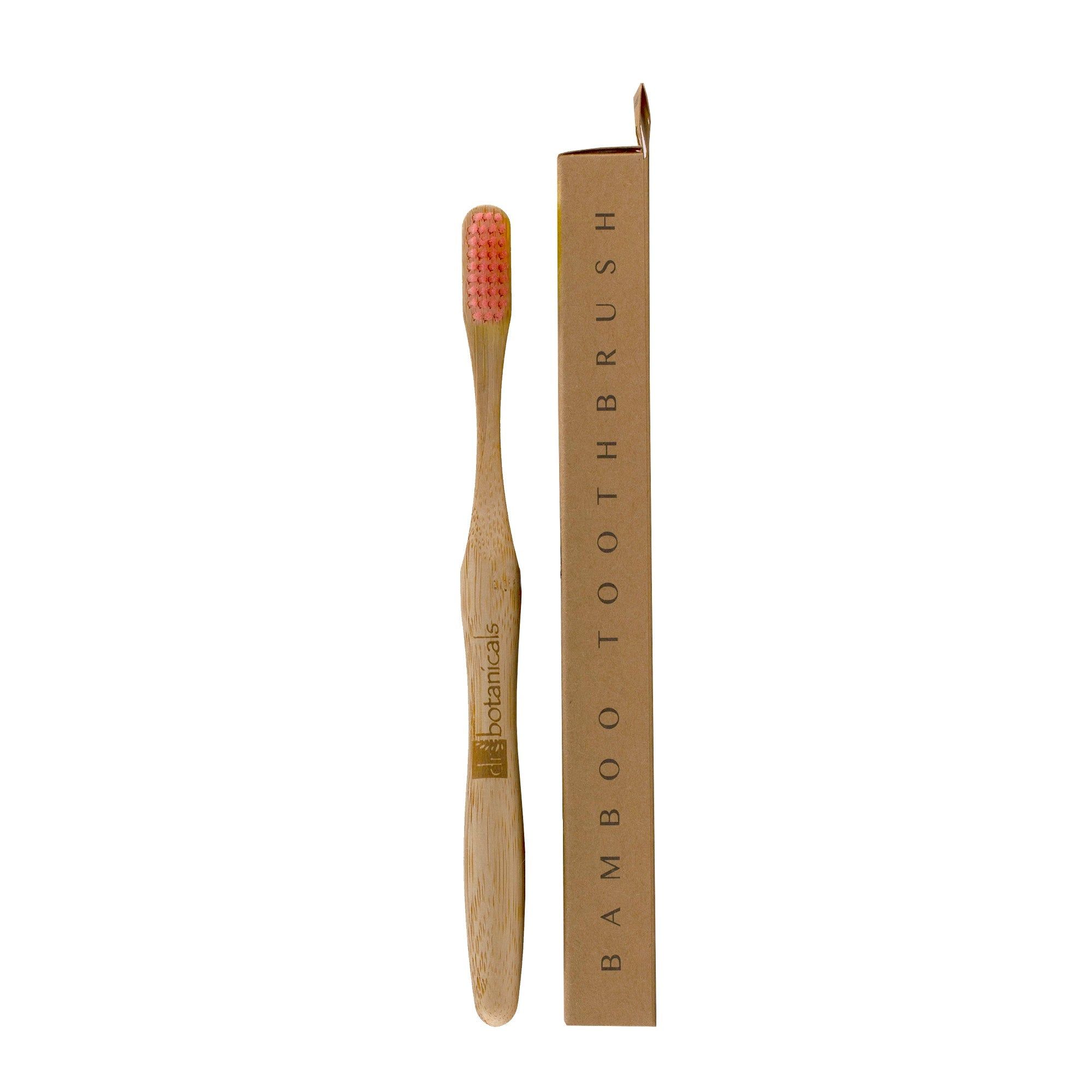 Bambus-Zahnbürste mit rosa Borsten und Verpackung. Aufschrift: "Bamboo Toothbrush". Marke: Dr Botanicals.