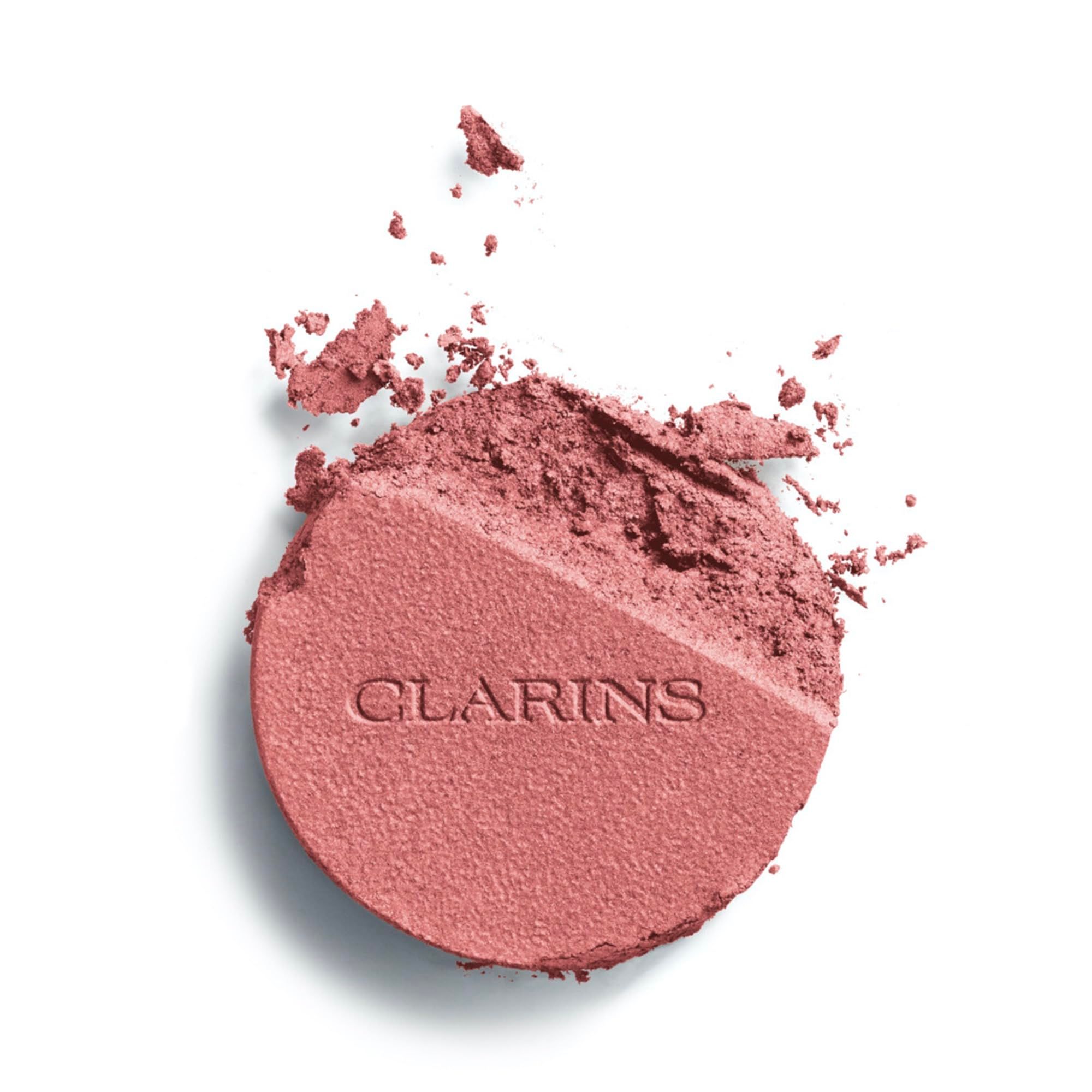 Zerkrümeltes Rouge in Rosa. Clarins-Logo auf der linken Seite. Helle Oberfläche.