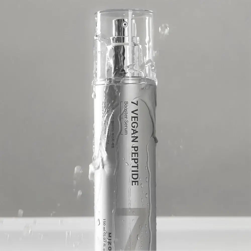 Silberne Flasche mit Sprühkopf. Aufschrift "7 Vegan Peptide Booster Serum". Wasser spritzt auf die Flasche. Klare Kappe.