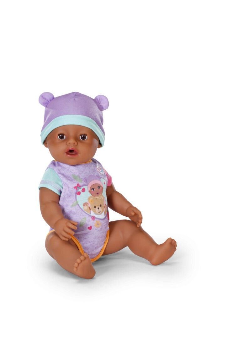BABY born Puppe mit lila Mütze und Strampler. Puppe sitzt. Hautfarbe: braun.