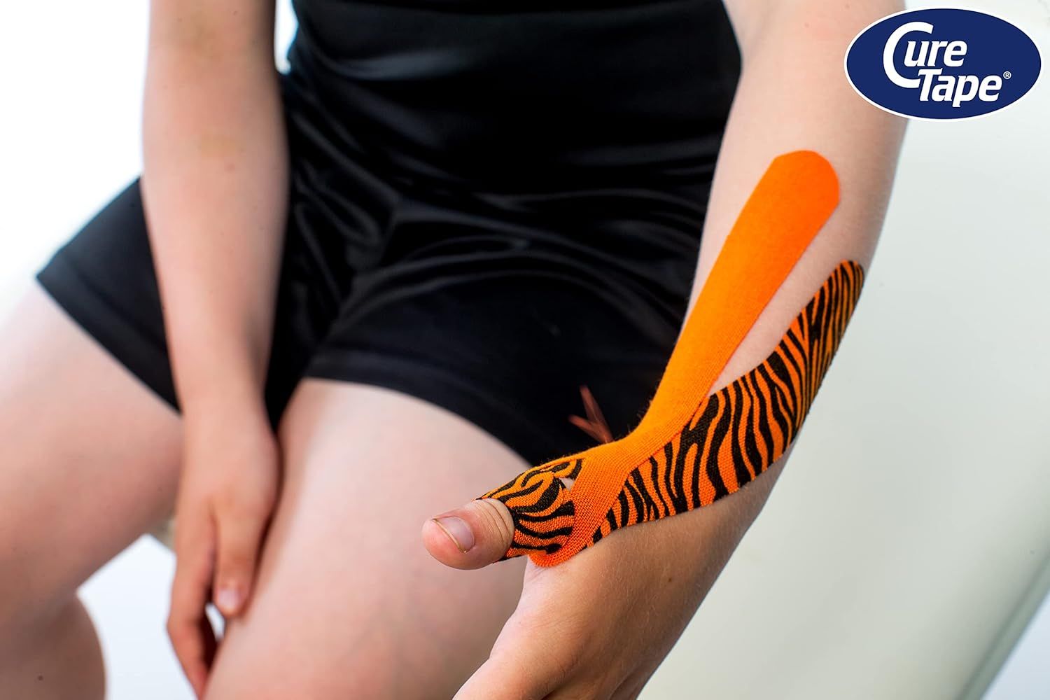 Arm mit CureTape Tiger. Orange mit schwarzen Streifen. Tape am Arm angebracht. CureTape Logo sichtbar.