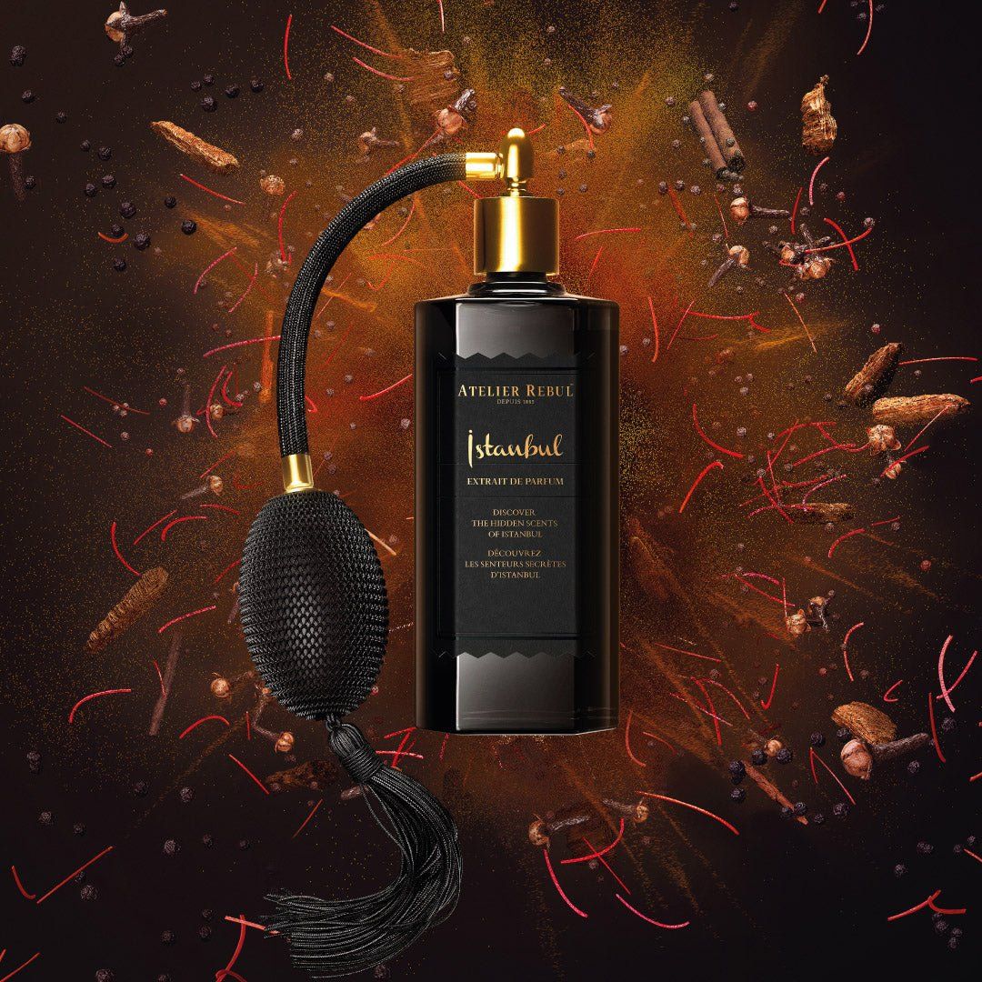 Schwarzer Flakon mit goldfarbenem Zerstäuber und Quaste. Aufschrift "Istanbul Extrait de Parfum". Hintergrund mit Gewürzen.
