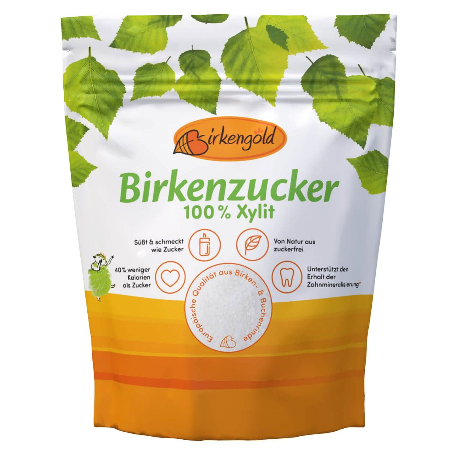 Verpackung von Birkengold Birkenzucker. Weißer Beutel mit grünen Blättern und orangefarbenem Streifen. Text: Birkenzucker, 100% Xylit.