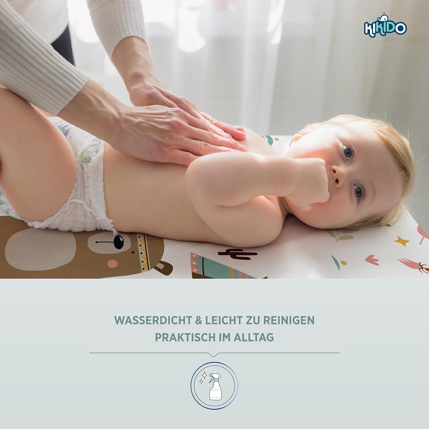 Baby liegt auf Wickelauflage. Hände berühren den Bauch des Babys. Text: Wasserdicht & leicht zu reinigen. Praktisch im Alltag.