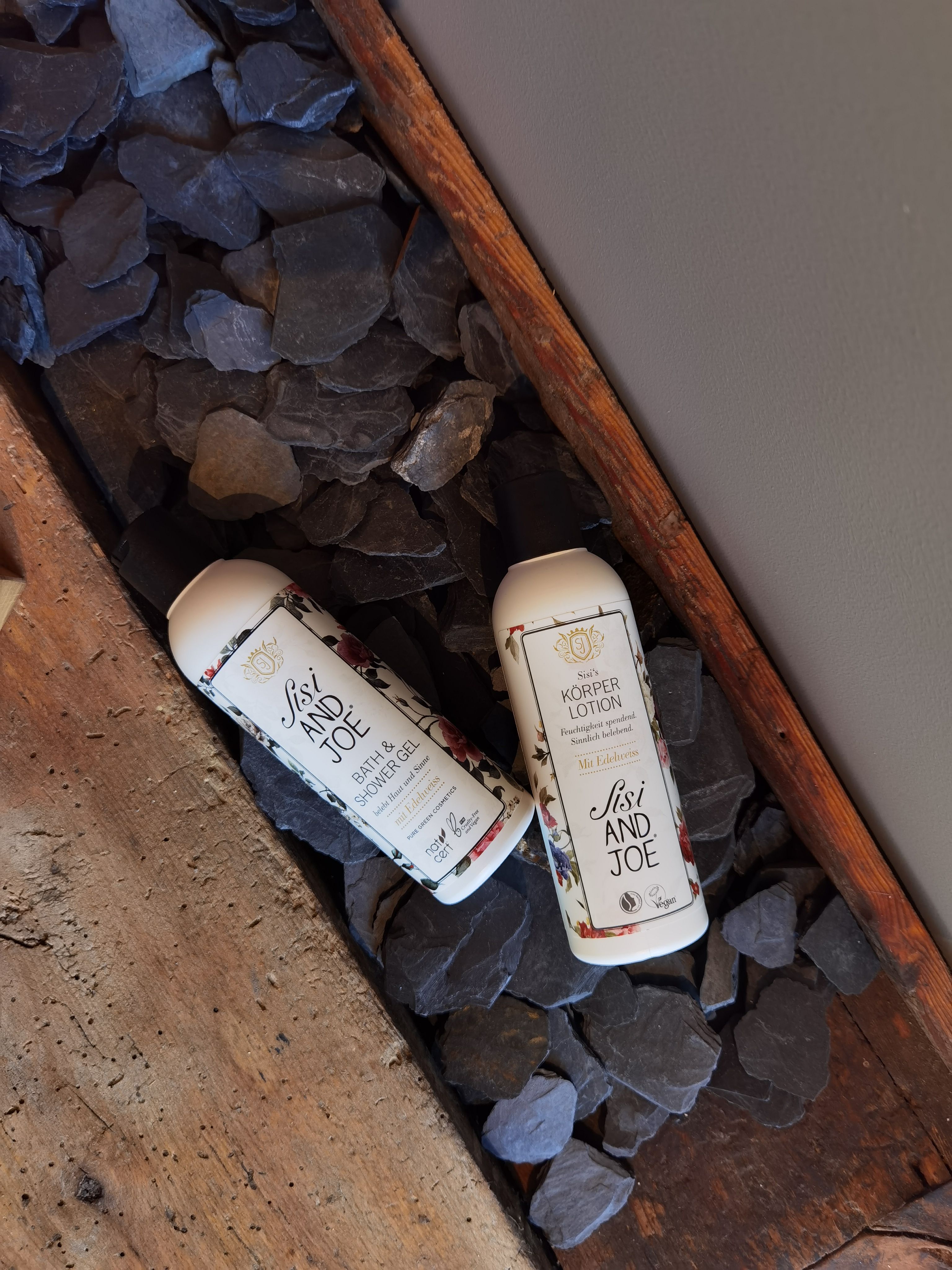 Zwei Flaschen Bath & Shower Gel. Weiße Flaschen mit floralem Muster und Etikett. Aufschrift: Sisi and Joe, Bath & Shower Gel.