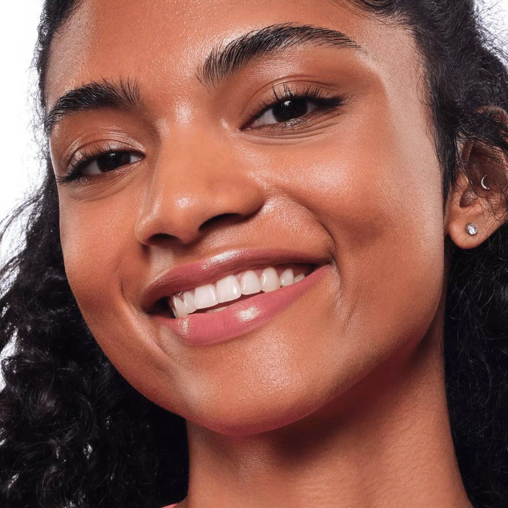 Porträt einer Frau mit rosafarbenem Lippenstift. Sie lächelt.