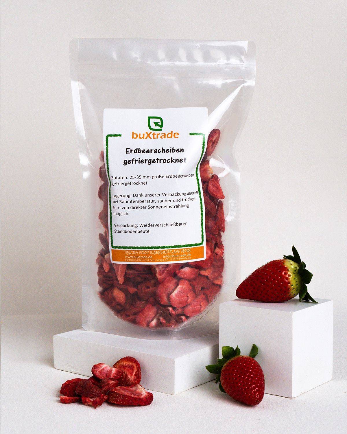 Transparente Tüte mit gefriergetrockneten Erdbeerscheiben. Aufkleber mit Produktinformationen. Frische Erdbeeren daneben.
