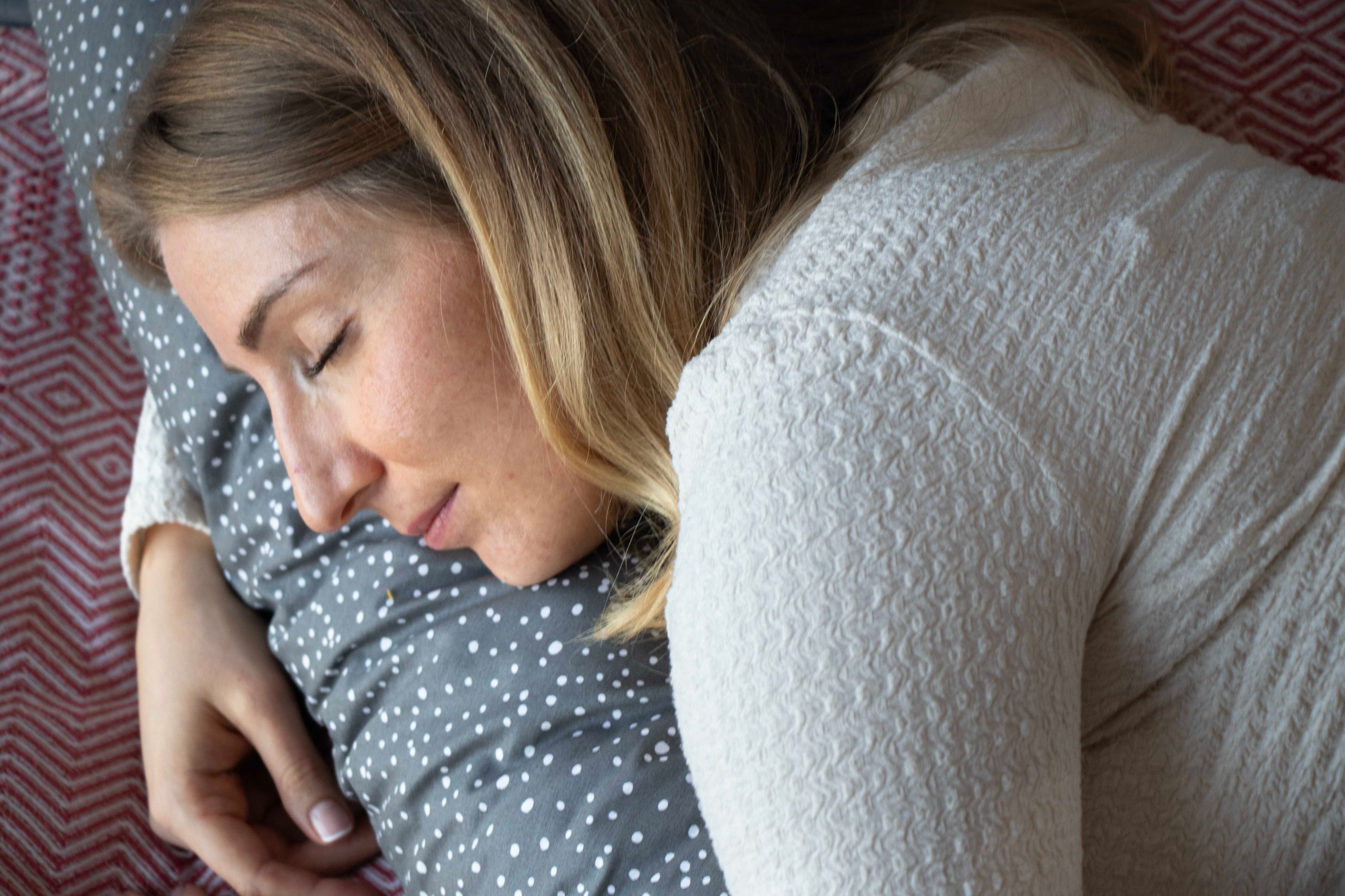 Nahaufnahme einer Frau, die auf einem Kissen mit weißen Punkten liegt.