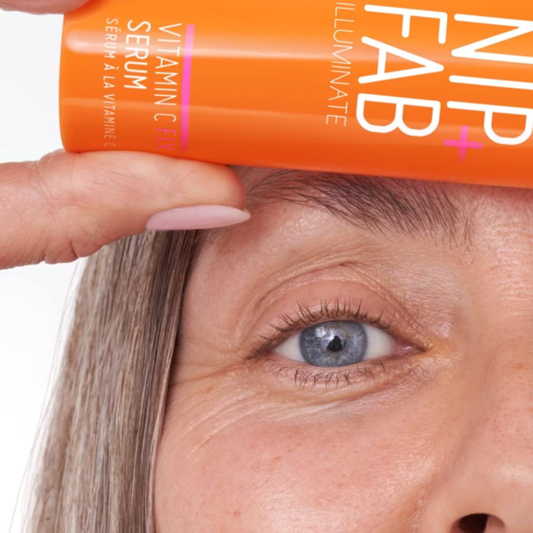 Nahaufnahme eines Auges und einer orangefarbenen Flasche. Aufschrift: NIP+FAB, ILLUMINATE, Vitamin C Fix Serum.