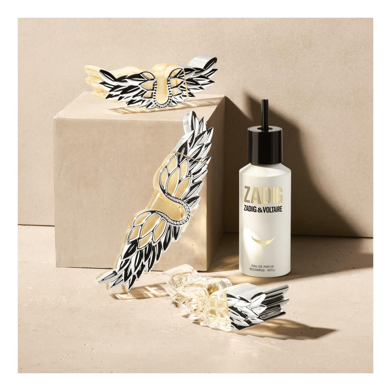 Zadig & Voltaire Flakon und Flügel-Embleme auf quadratischem Podest. Produktpräsentation, mehrere Elemente.