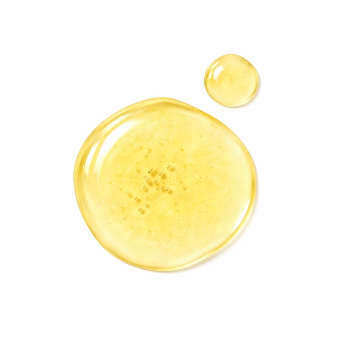 Zwei gelbe Flüssigkeitstropfen auf weißem Hintergrund. Der größere Tropfen hat Bläschen.