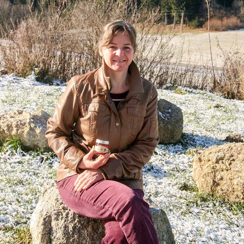 Frau hält ein kleines Glas mit rotem Inhalt und silbernem Deckel.