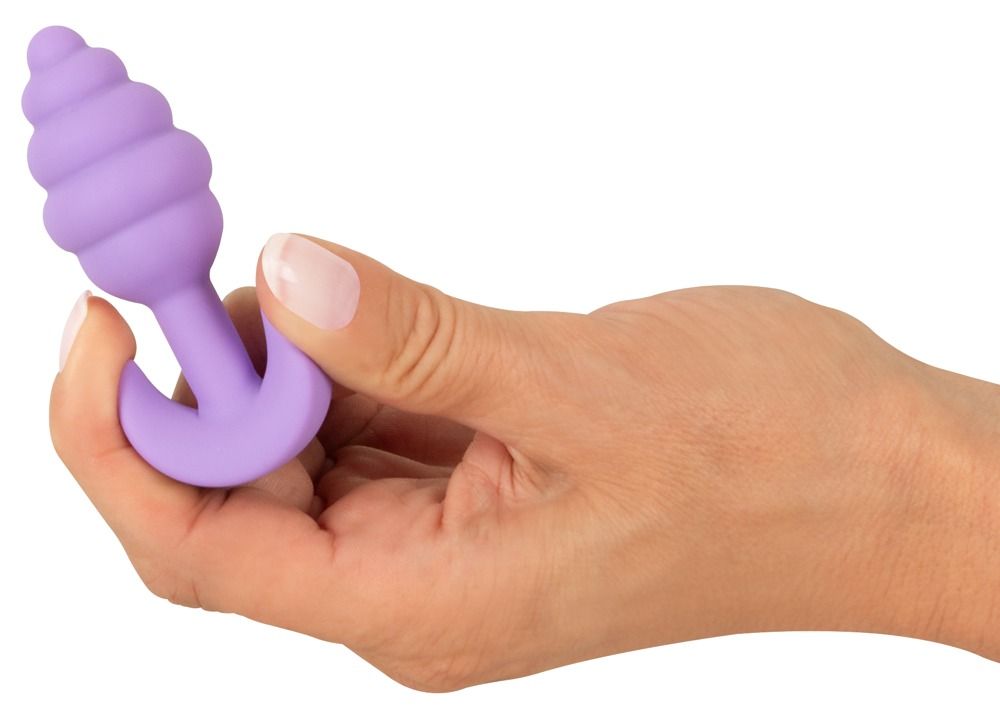 Hand hält lila Analplug. Geriffelte Spitze, T-Griff. Weiches Material.