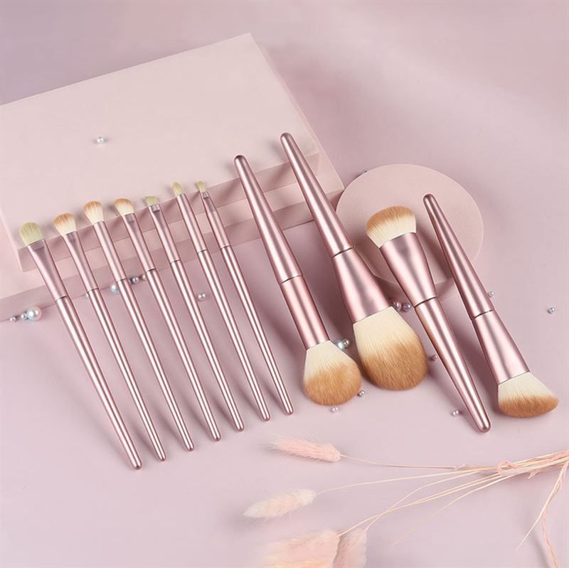 Set von Make-up-Pinseln. Rosa Griffe, helle Borsten. Verschiedene Formen und Größen. Auf rosa Untergrund.
