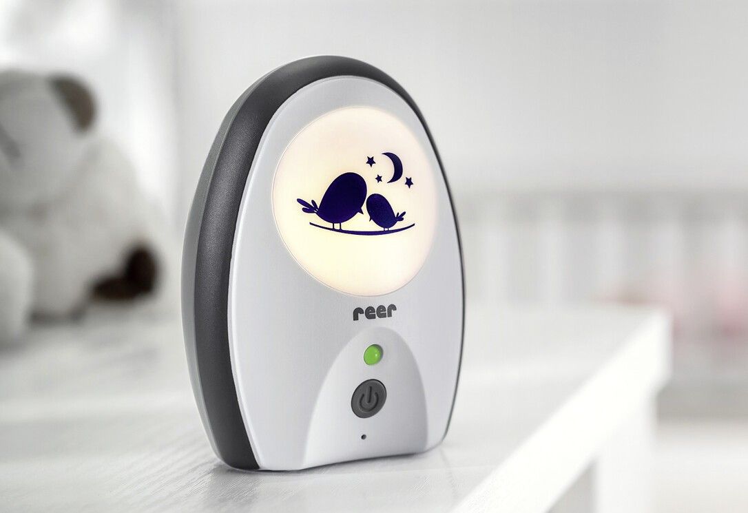 Ein Babyphone mit Nachtlichtfunktion und Vogelmotiv auf einem Nachttisch.