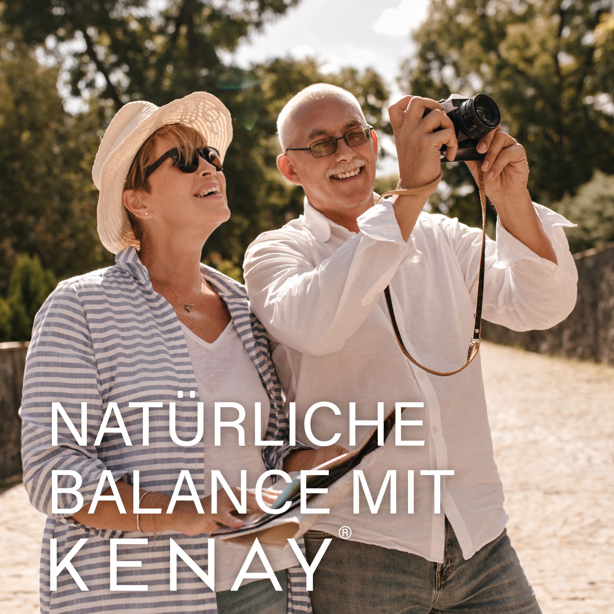 Älteres Ehepaar im Freien. Mann fotografiert mit Kamera. Text: "NATÜRLICHE BALANCE MIT KENAY".