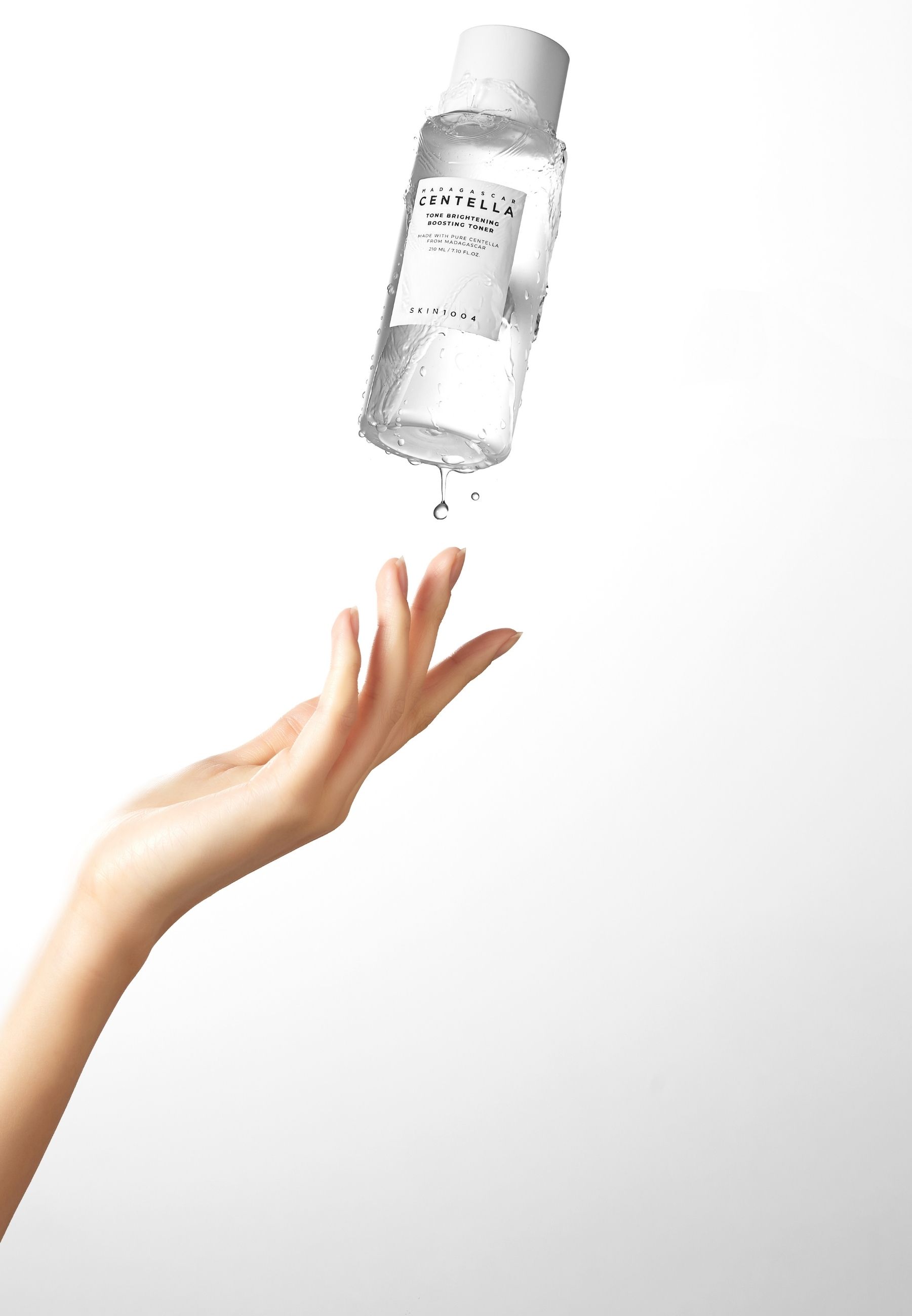 Eine Hand fängt einen Tropfen Flüssigkeit auf, die aus einer Flasche tropft. Flasche mit Produktetikett.