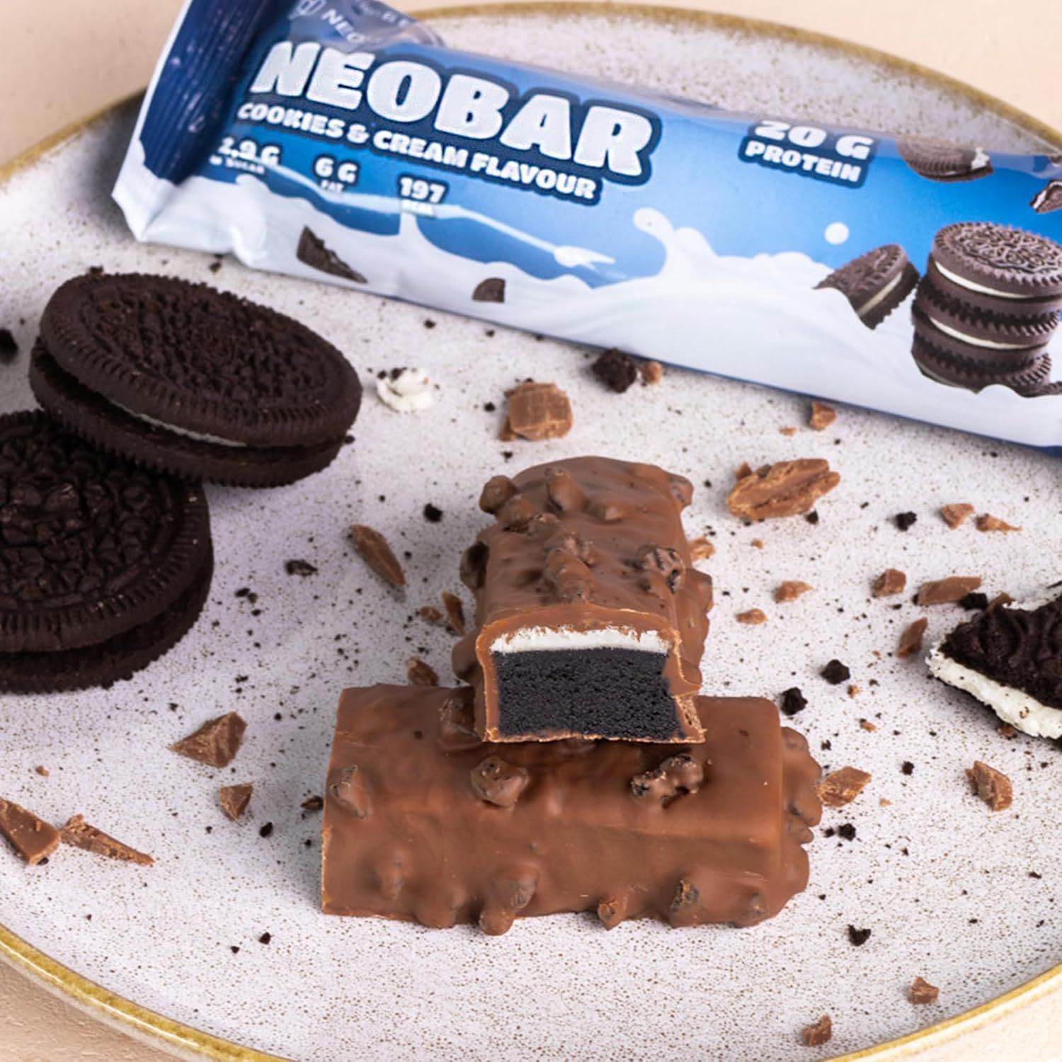 Zwei angeschnittene Proteinriegel mit Schokoladenüberzug und Cookie-Stückchen. Aufschrift: NeoBar Cookies & Cream Flavour, 20g Protein.