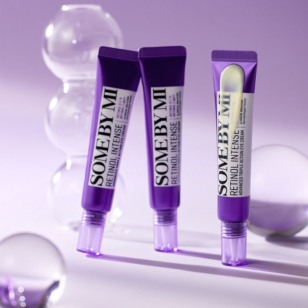 Drei lila Tuben SOMEBYMI Retinol Intense Advanced Triple Action Eye Cream, umgeben von Glaskugeln.
