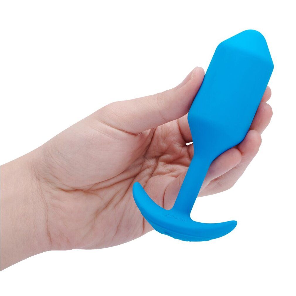 Hand hält blauen Plug. Plug tropfenförmig mit gebogener Basis. Hand mit heller Haut.
