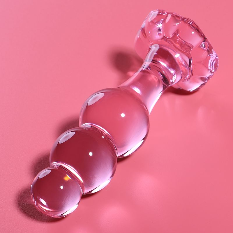 Rosa Glas-Analplug mit kugelförmigen Segmenten, auf rosa Hintergrund.