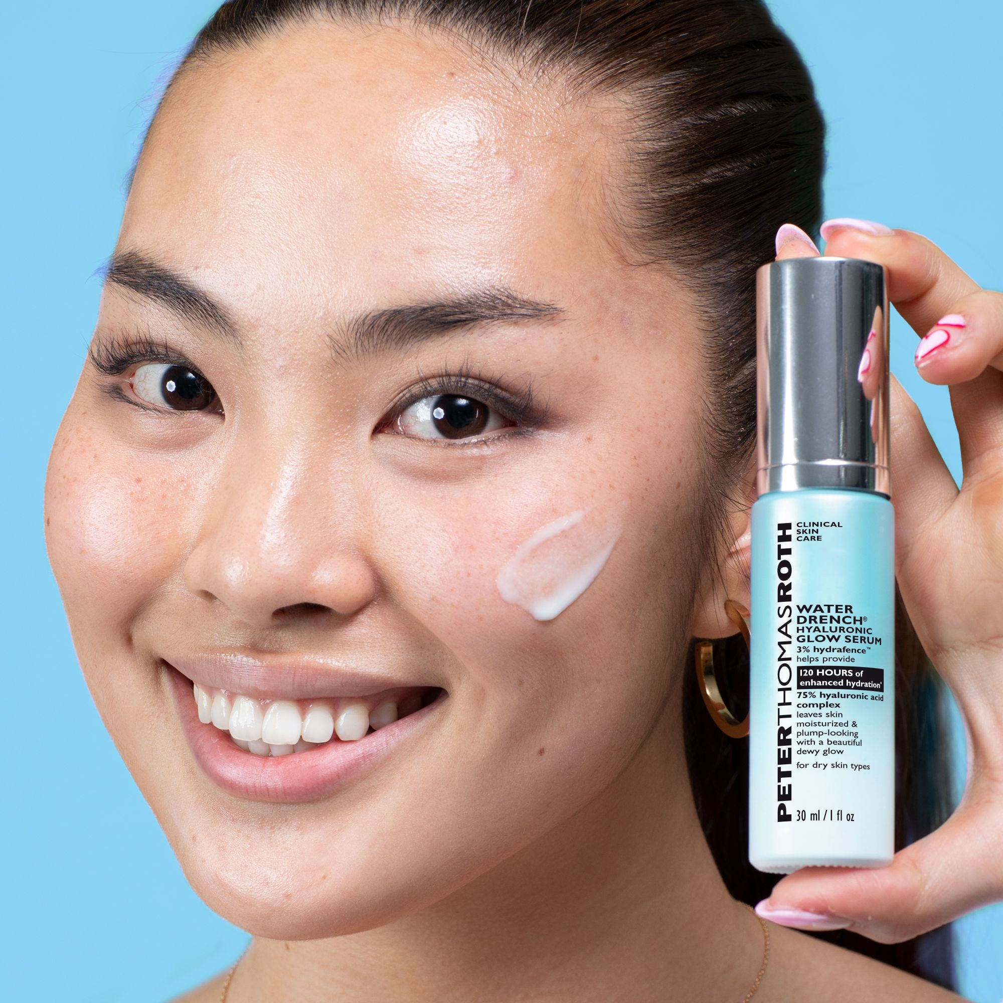 Frau hält Serumflasche. Aufschrift: Peter Thomas Roth Water Drench® Hyaluronic Glow Serum. Serum auf Gesicht aufgetragen.