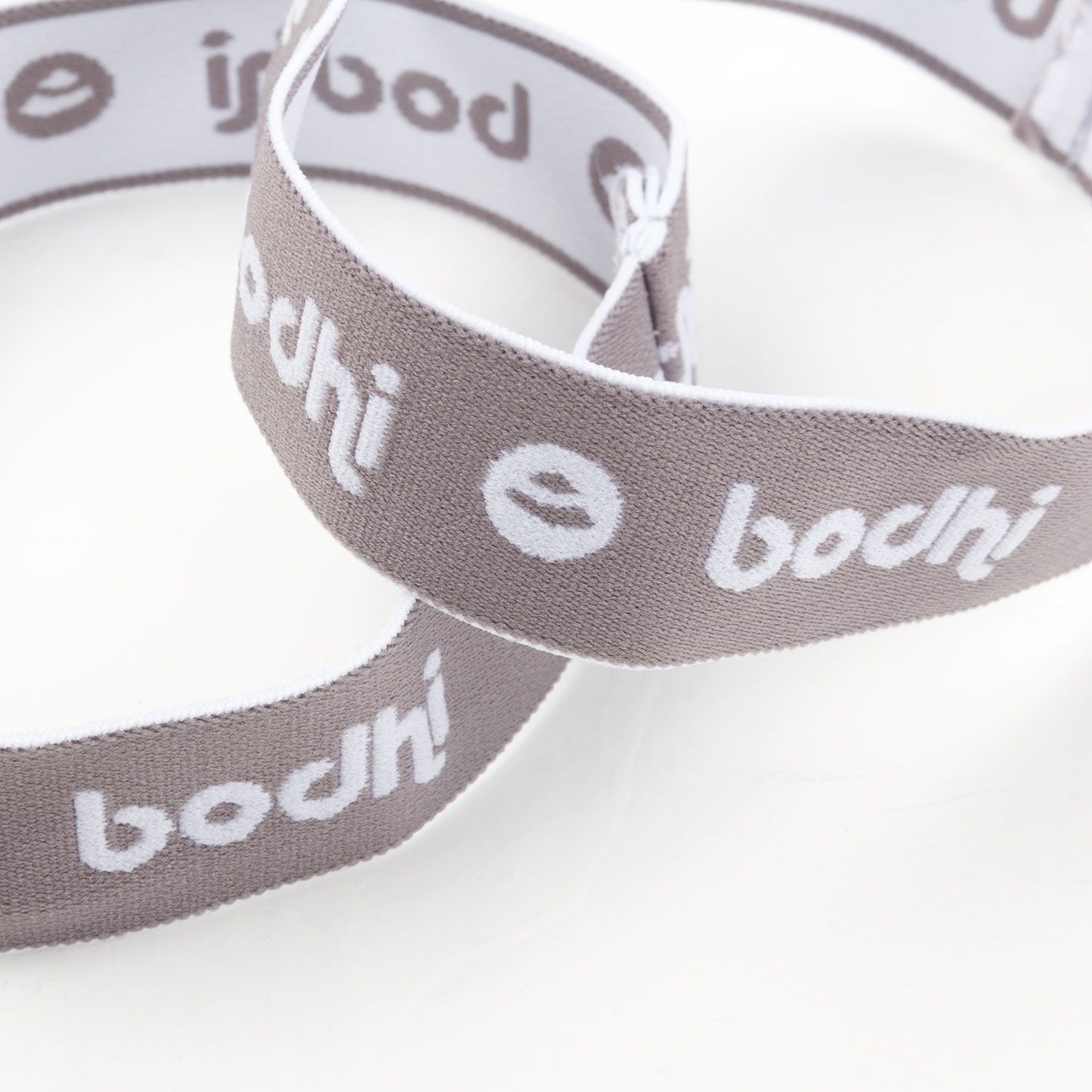 Nahaufnahme von zwei grauen Haltebändern mit weißem "bodhi"-Schriftzug. Elastisches Material.