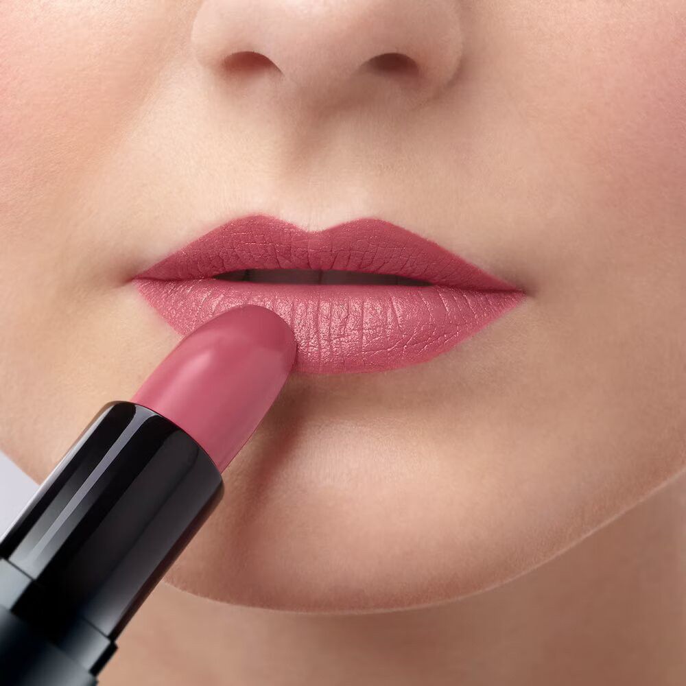 Person trägt einen rosafarbenen Lippenstift auf den Lippen auf.