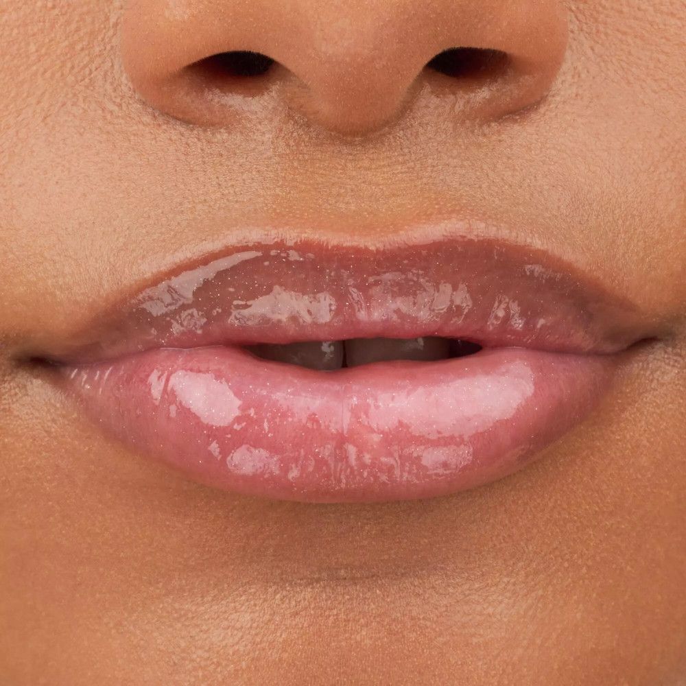 Nahaufnahme von Lippen mit glänzendem Lipgloss. Die Lippen sind leicht rosa getönt und glänzend.